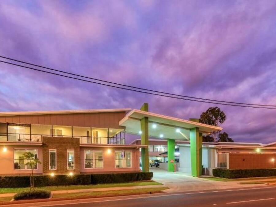Een hotel met een modern design, een tankstation ernaast en een goed verlichte ingang.