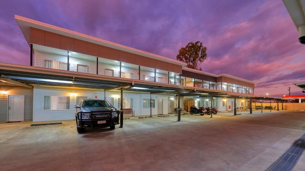 A multi-story hotel with a parking area in front.