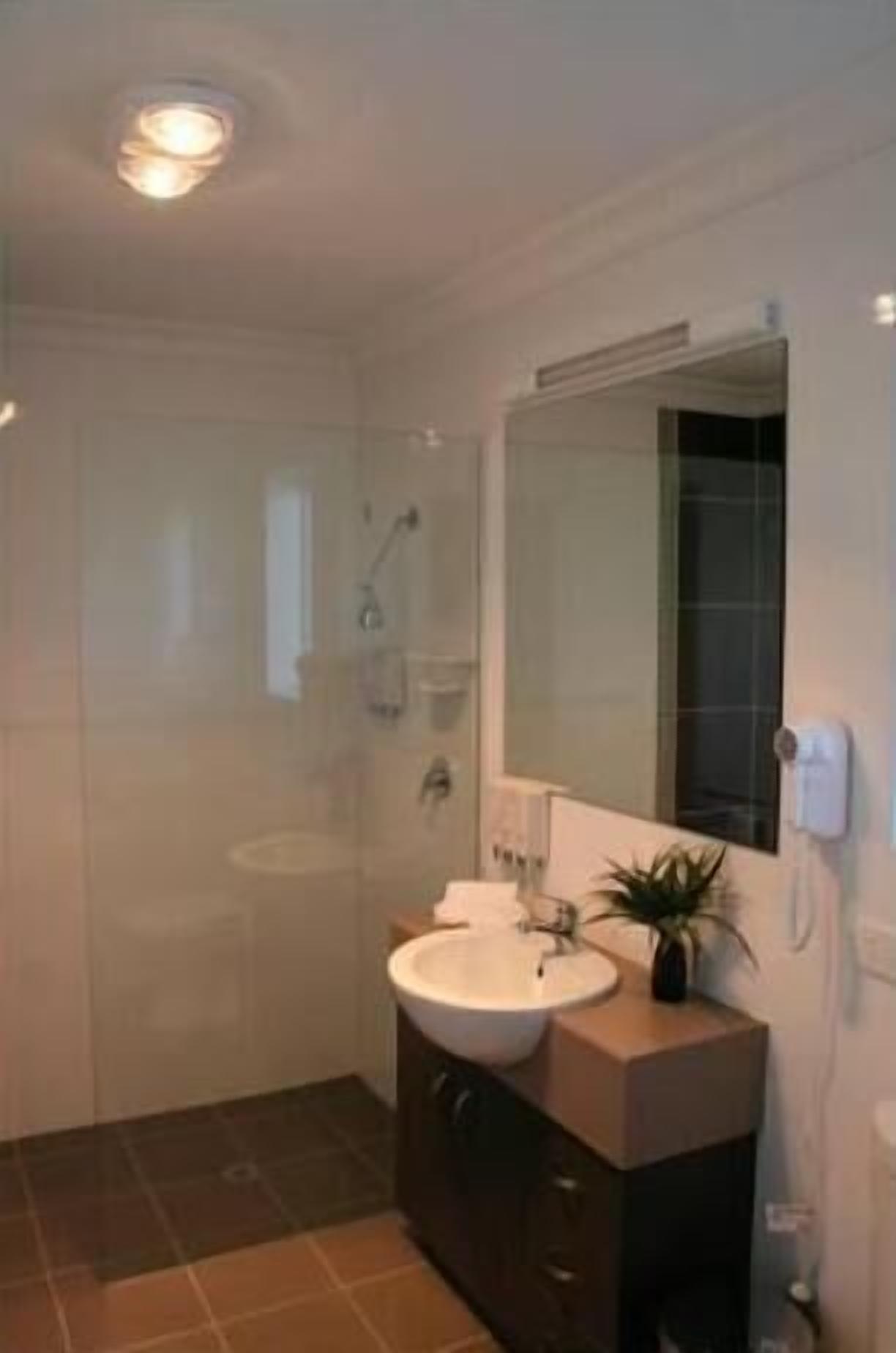 Un baño moderno con cabina de ducha de vidrio, un lavabo blanco y un espejo grande.
