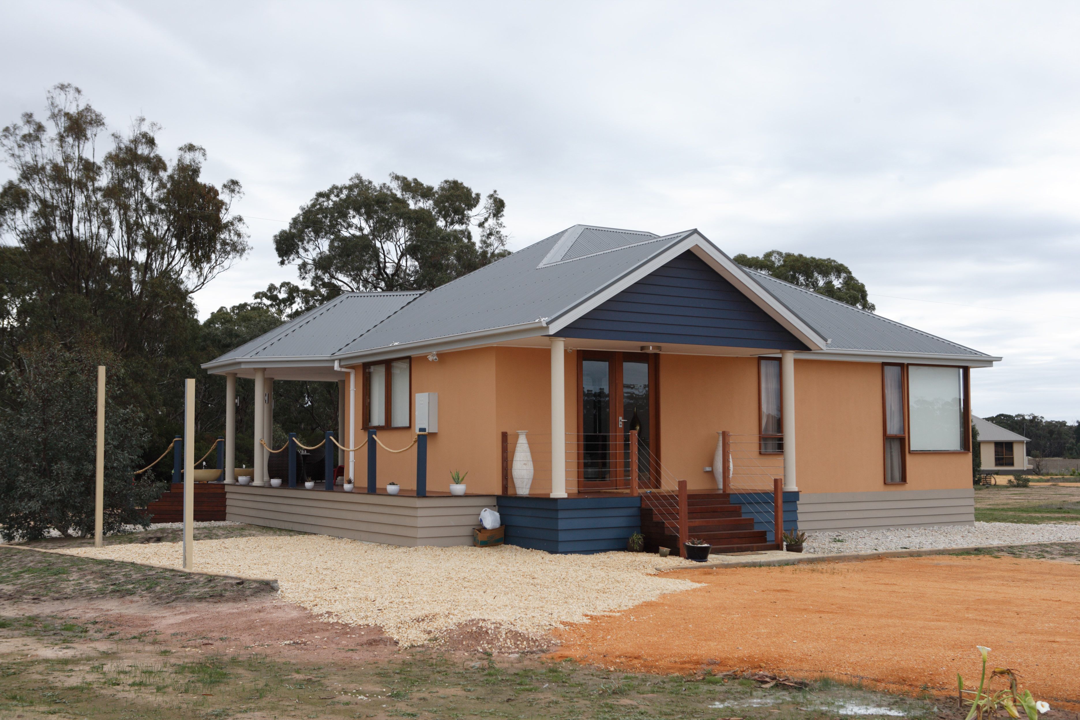A modern house with a covered porch, a front door, and a small front yard.