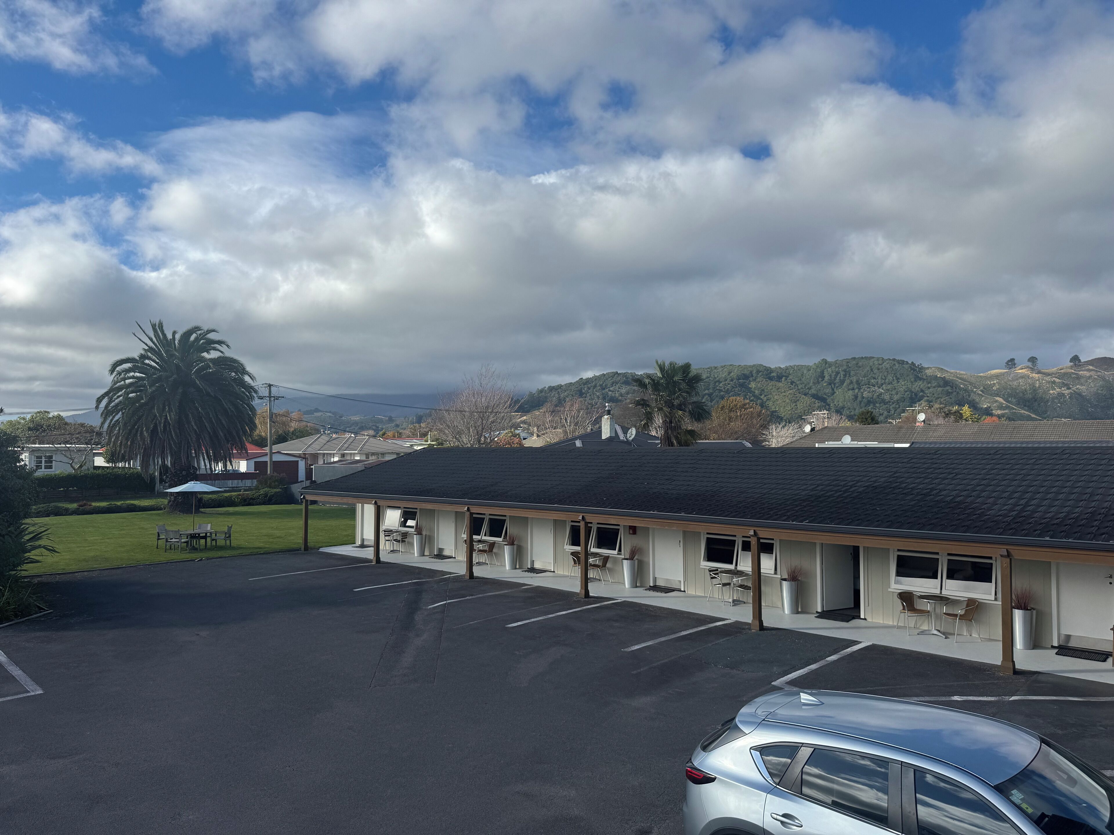 Un motel con estacionamiento, un área de estar al aire libre cubierta y vistas a colinas y montañas.