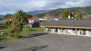 Ein Motel mit überdachtem Parkplatz, separaten Zimmern und Bergblick im Hintergrund.