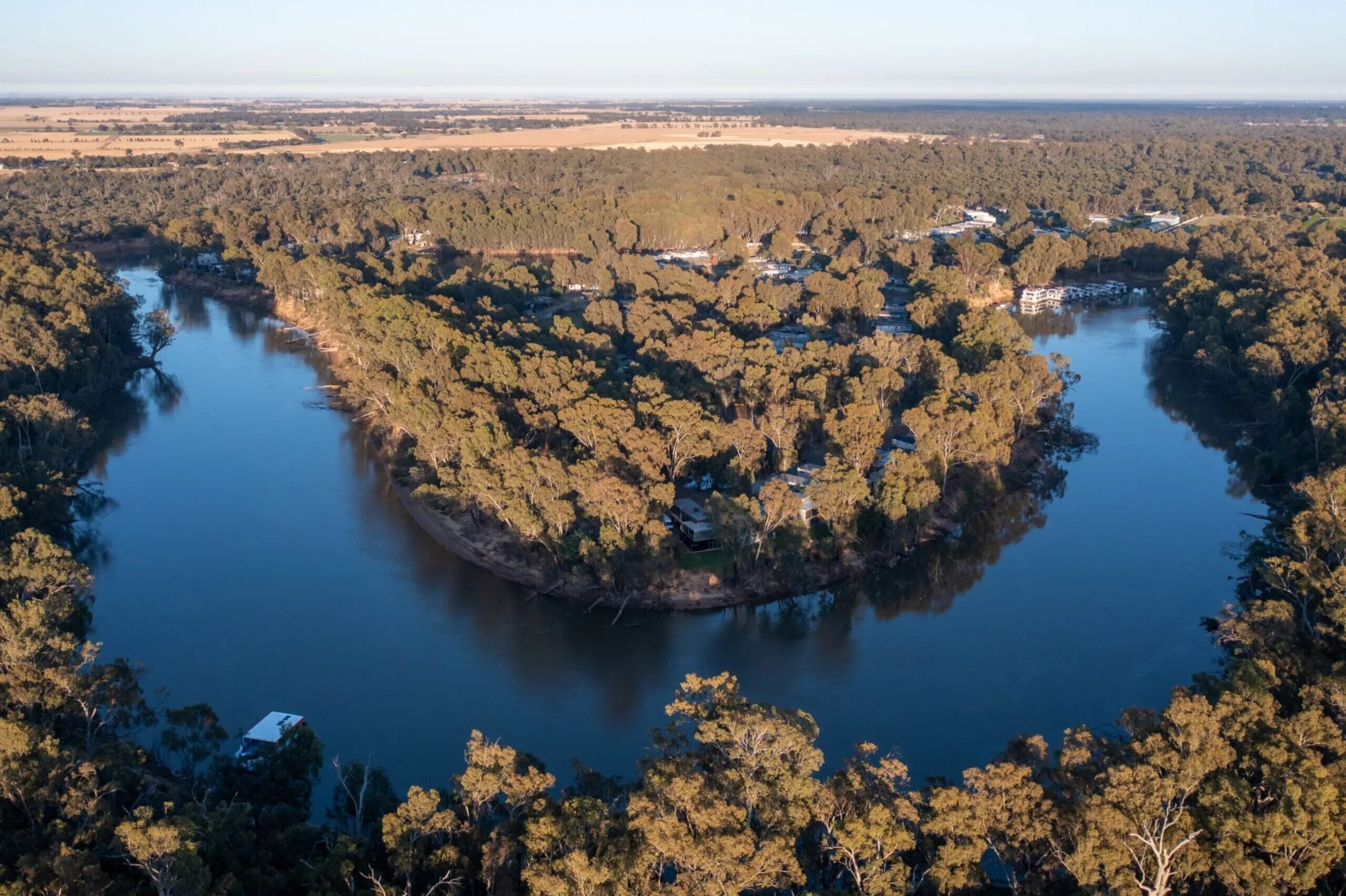 En vy över en sjö från ovan, omgiven av tät skog, och med flera byggnader synliga vid stranden.