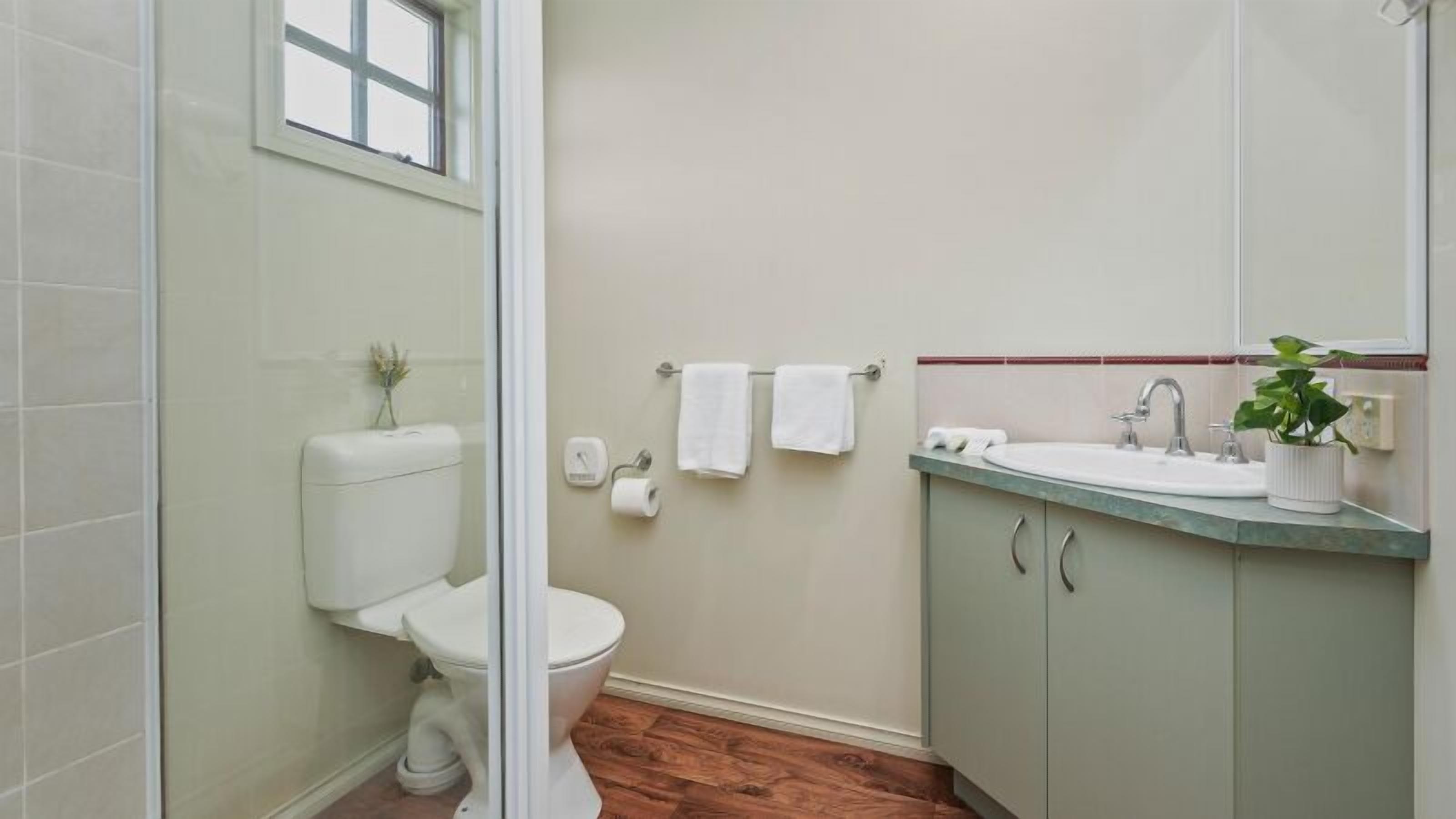 A bathroom with a toilet, sink, and a small window.