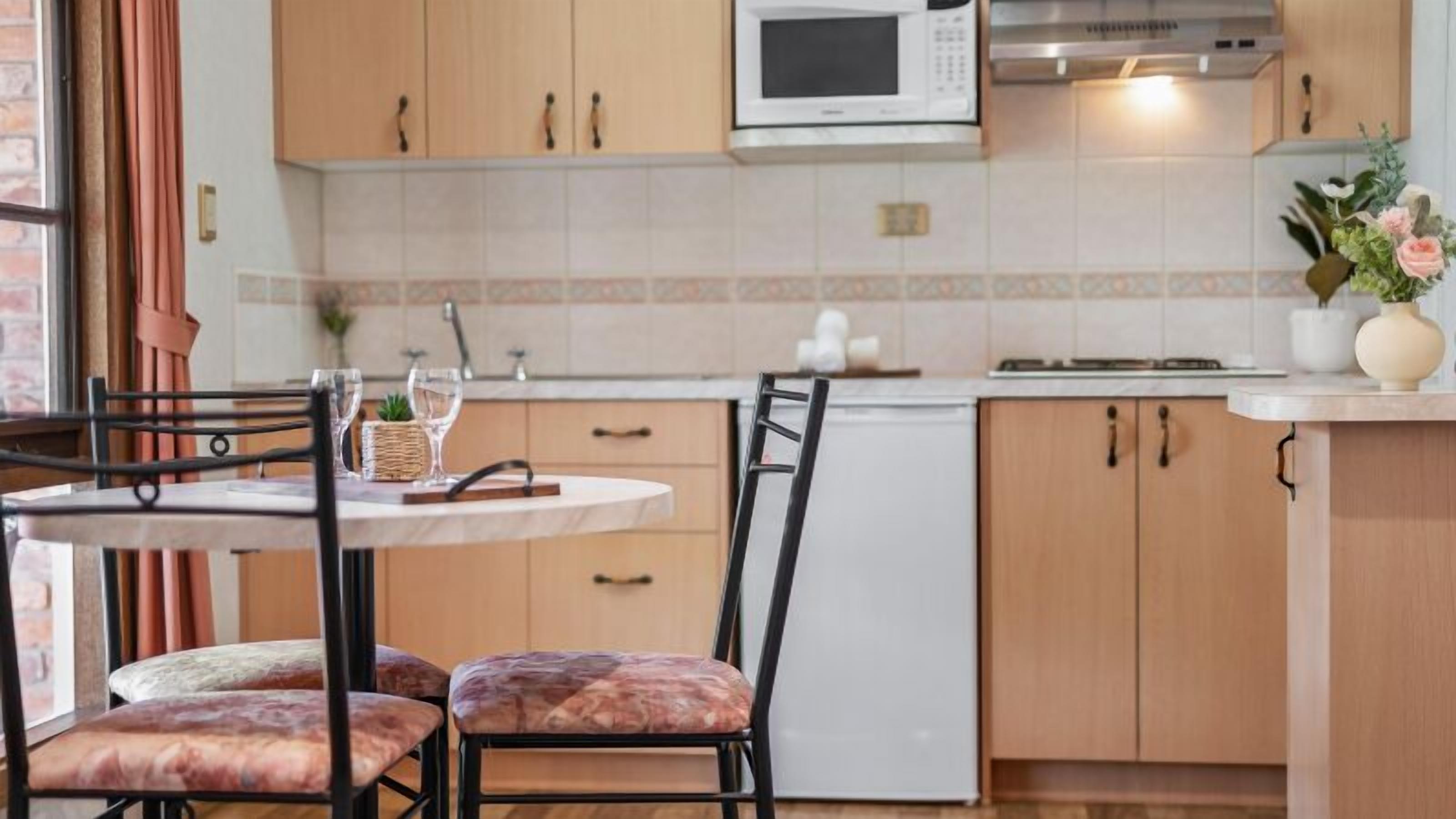Une cuisine moderne avec des meubles en bois, un micro-ondes blanc et un coin repas comprenant une table et des chaises.