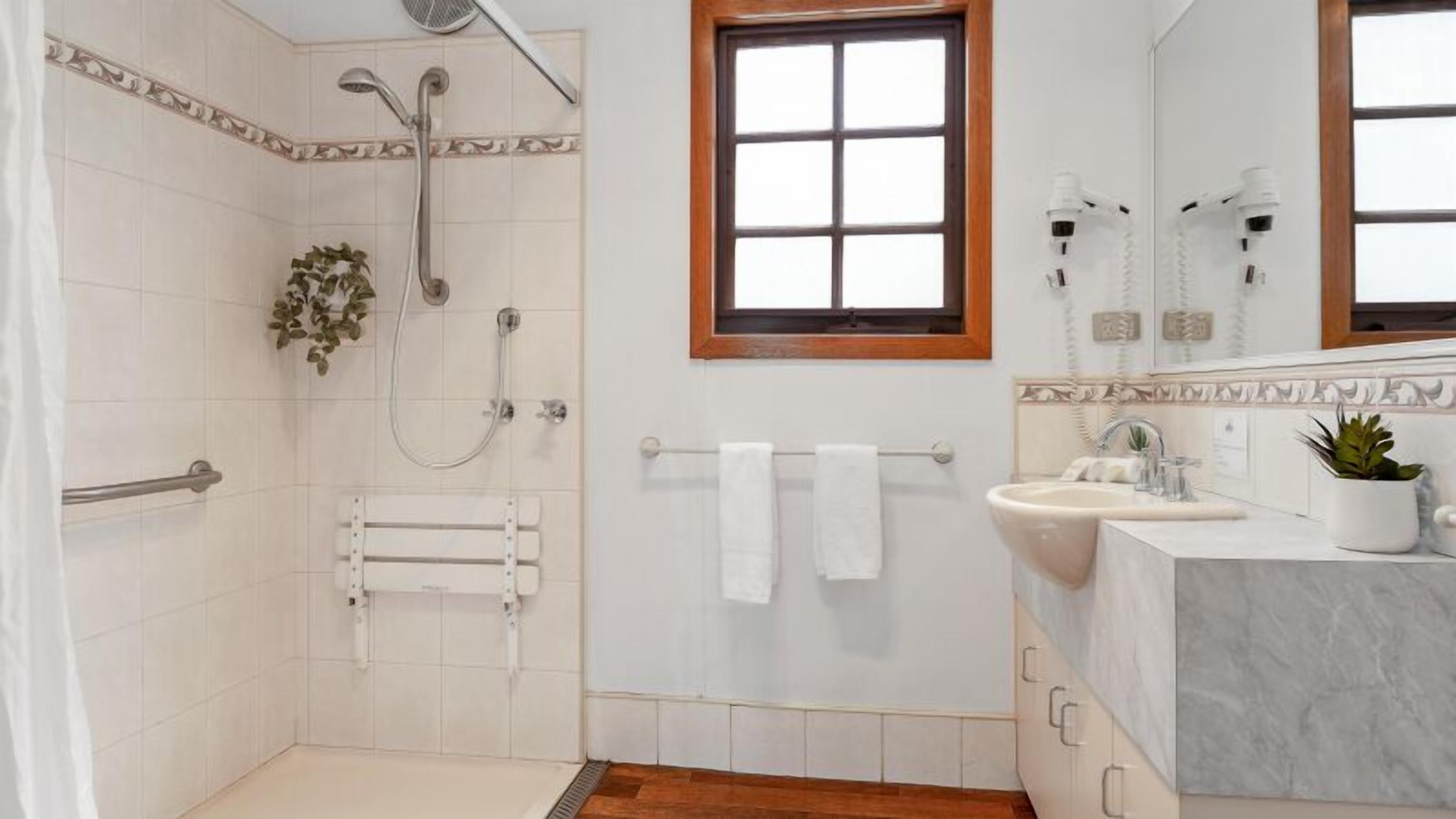 Ein Badezimmer mit Dusche, Waschbecken und Fenster.