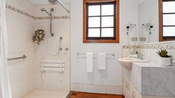 Ein Badezimmer mit Dusche, Waschbecken und Fenster.