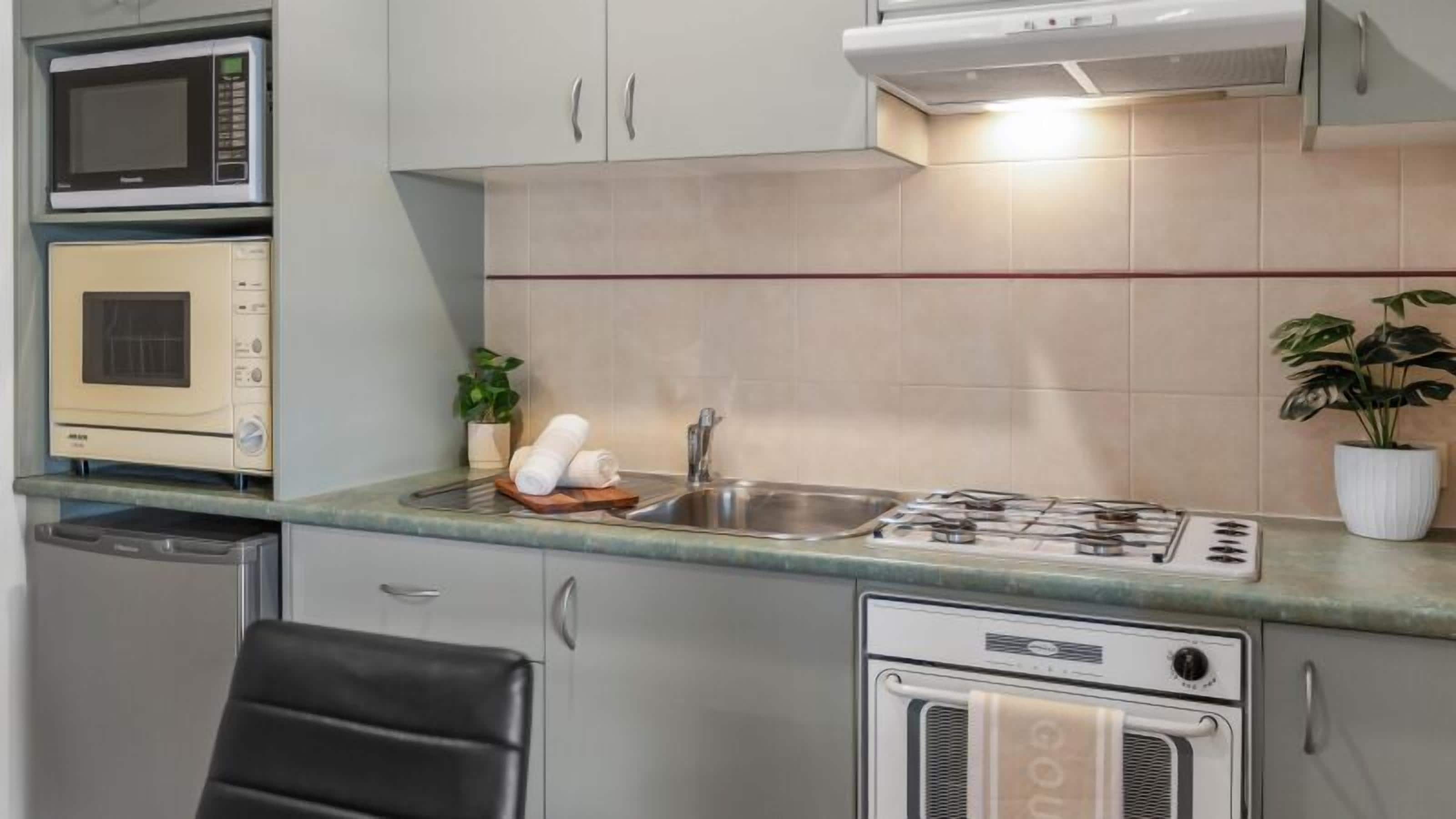 A compact kitchen with a microwave, oven, sink, and stove.
