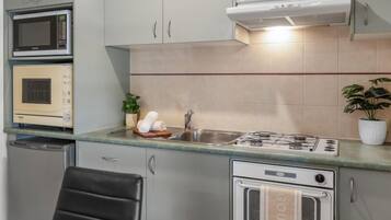 A compact kitchen with a microwave, oven, sink, and stove.
