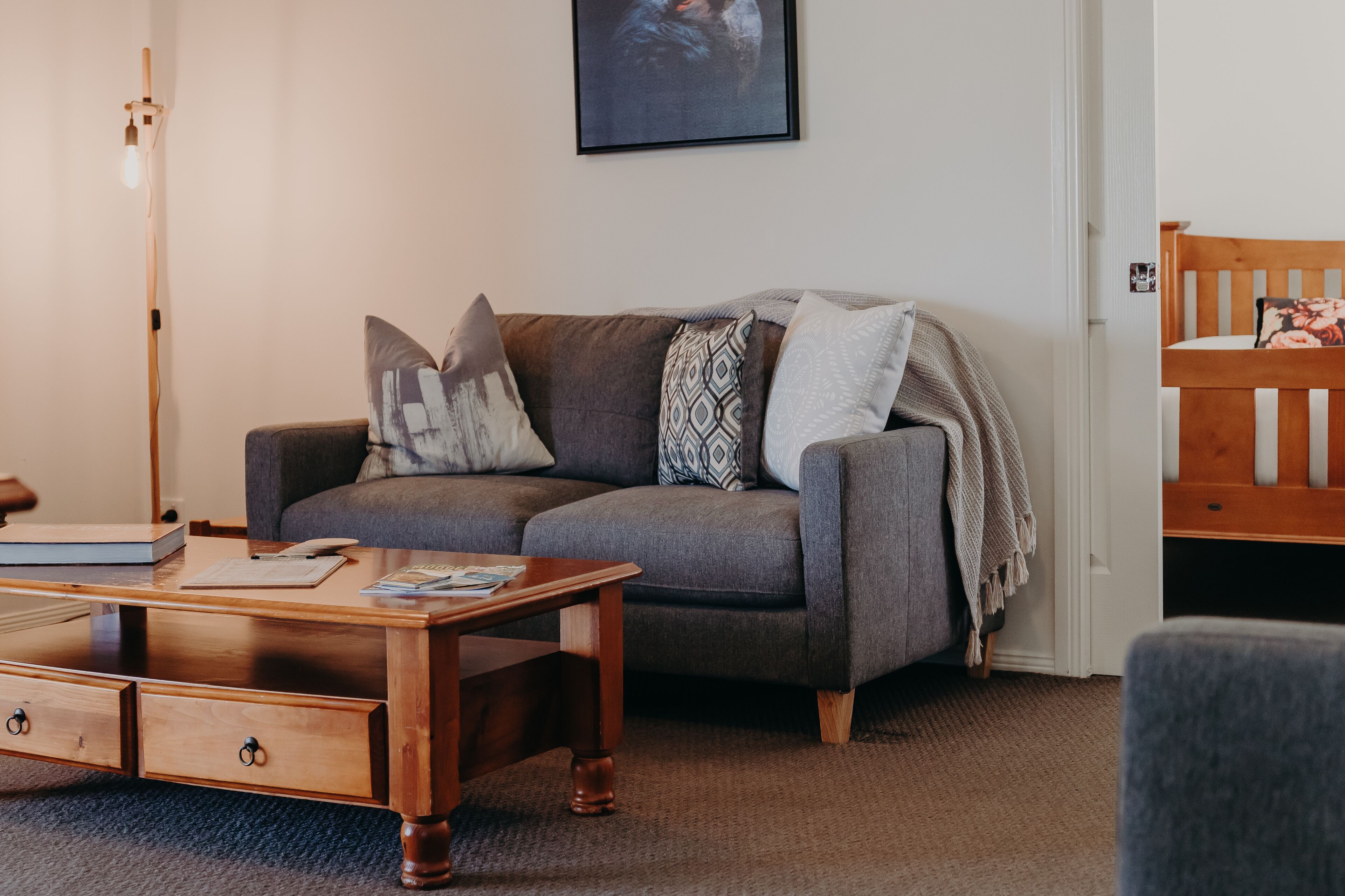 En hyggelig stue med en grå sofa, et træbord og en gulvlampe.