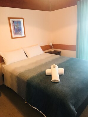 A hotel room with a bed, a nightstand, a lamp, and a framed picture on the wall. - Lighthouse Beach Holiday Village (Port Macquarie)