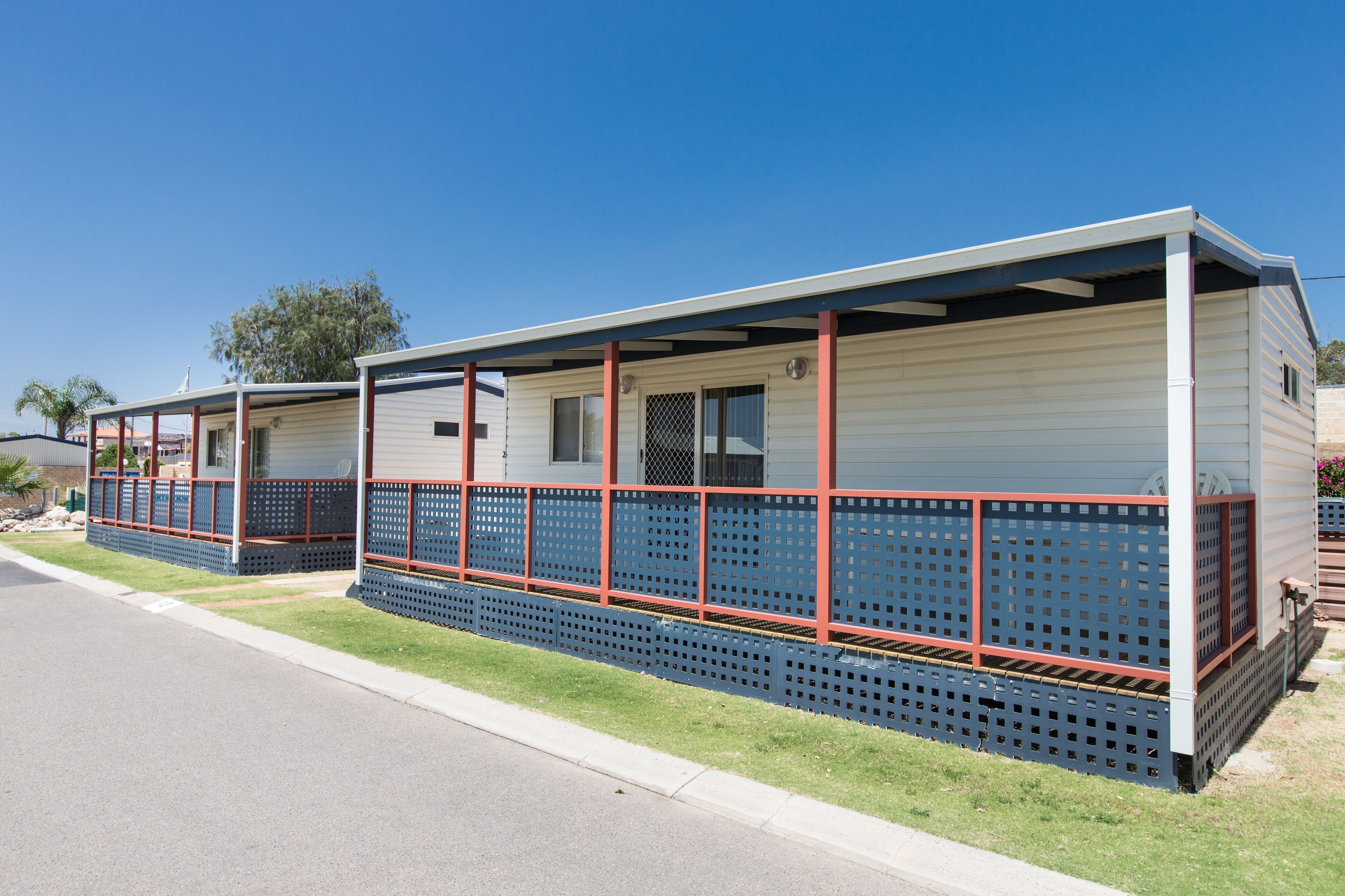 A row of mobile homes with a covered porch and a fenced area.