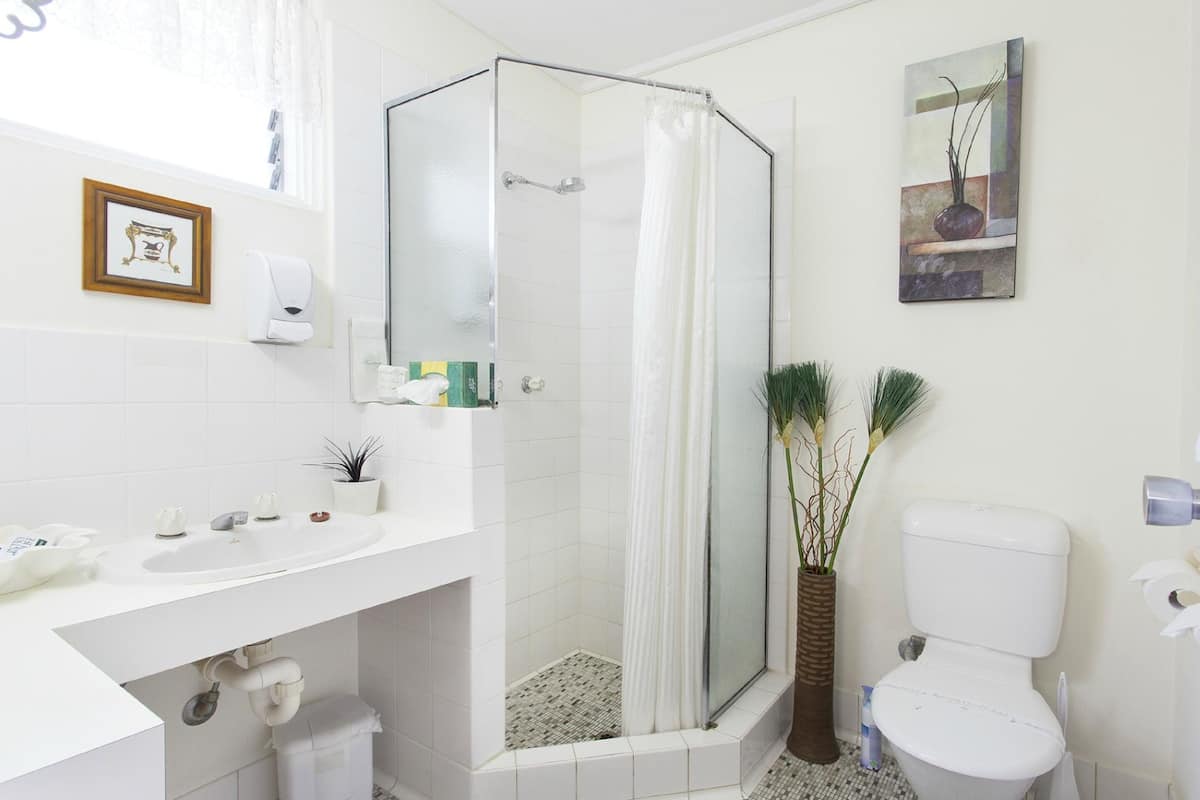 Un baño moderno con cabina de ducha de vidrio, inodoro blanco y lavamanos con espejo.
