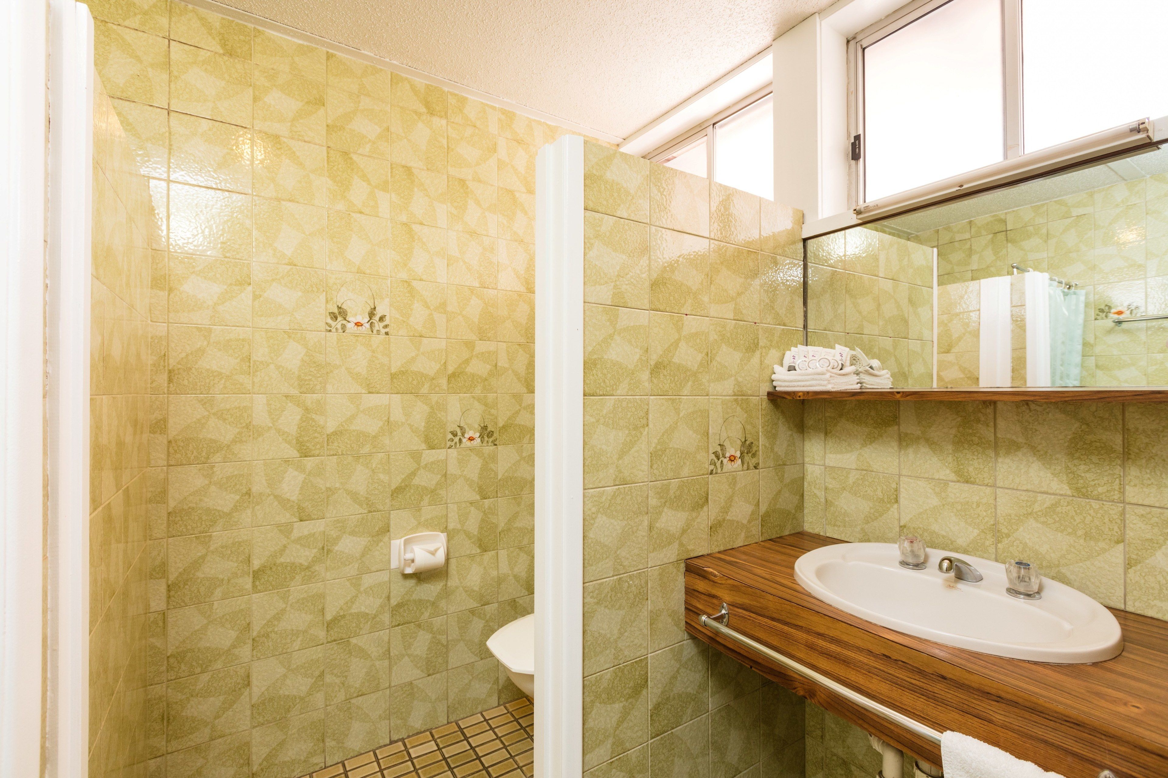 A bathroom with patterned tiles, a wooden vanity, a sink, a toilet, and a mirror.