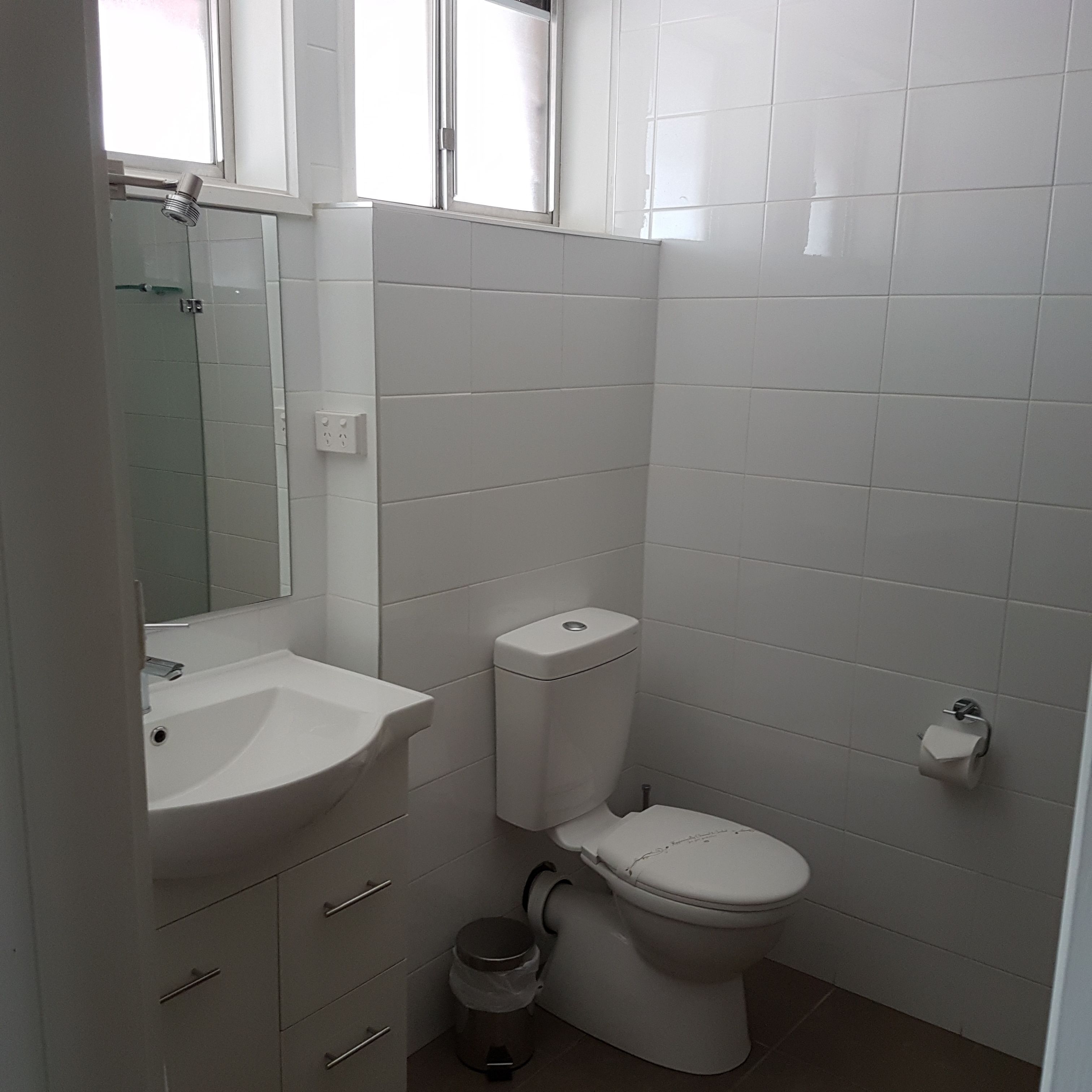A bathroom with a white sink, toilet, and mirror.