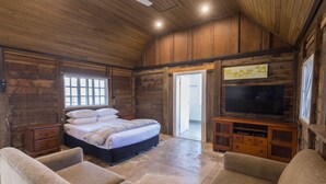 A rustic wooden room with a bed, a television, and a sofa. - NRMA Lake Somerset Holiday Park (Hazeldean)
