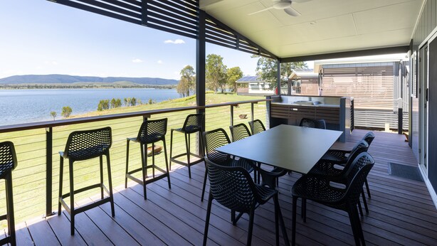 A covered outdoor area with a table and chairs, overlooking a lake and hills. - NRMA Lake Somerset Holiday Park (Hazeldean)