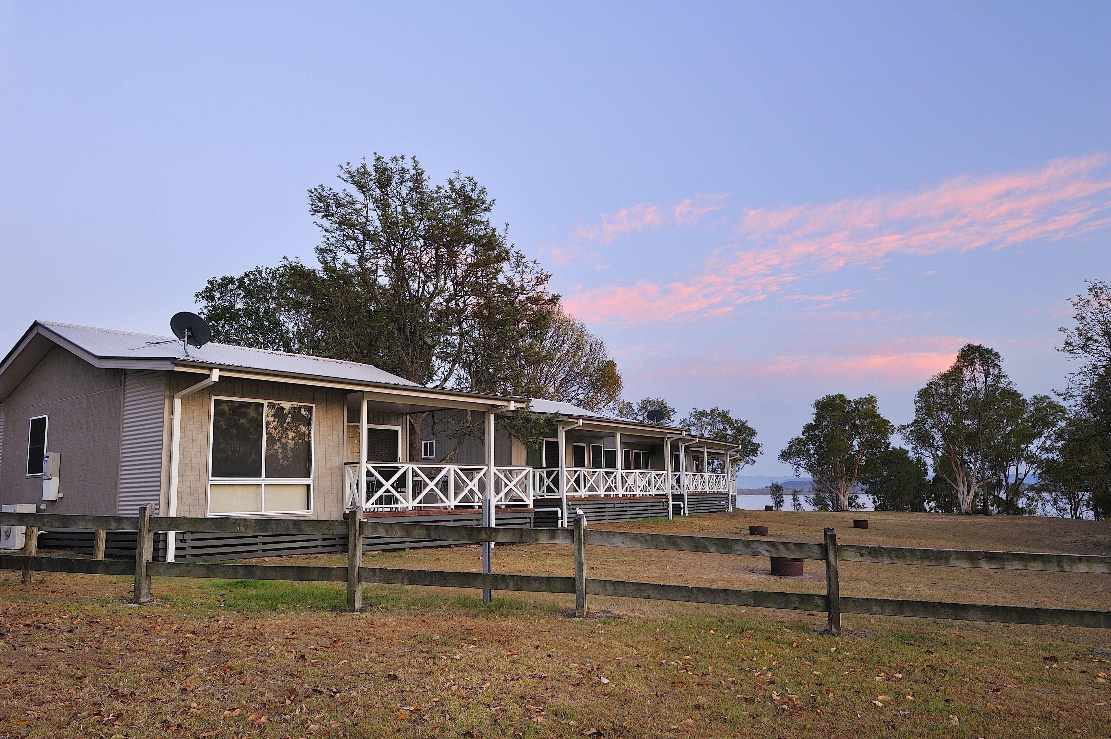 A single-story building with a porch, a satellite dish, and a view of the water.