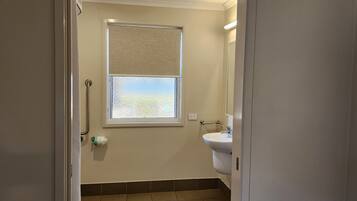 Un baño con ventana, lavamanos y un perchero para toallas.