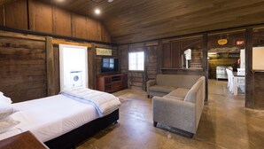 A spacious room with a bed, a sofa, a television, and a kitchen area. - NRMA Lake Somerset Holiday Park (Hazeldean)