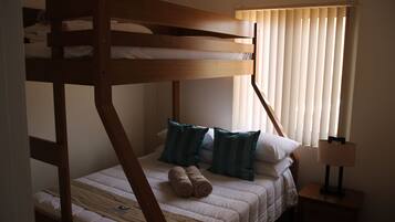 A bunk bed with a wooden frame, two pillows, and rolled towels on the lower bed.