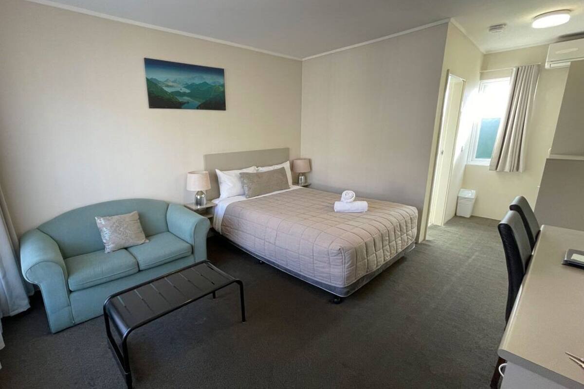 Une chambre d’hôtel avec un lit, un canapé, une petite table et un tableau au mur.