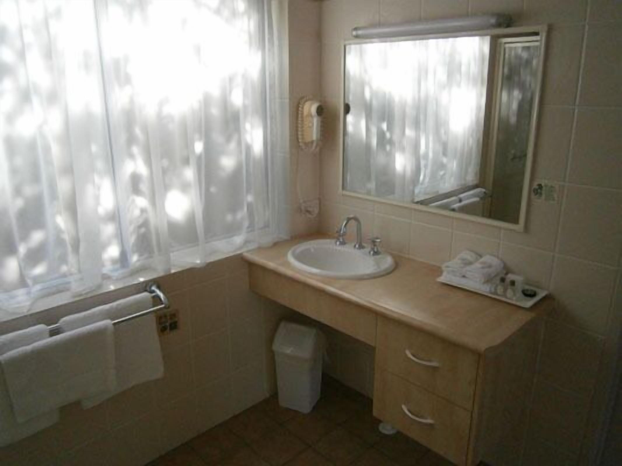 A bathroom with a sink, mirror, and towel rack.