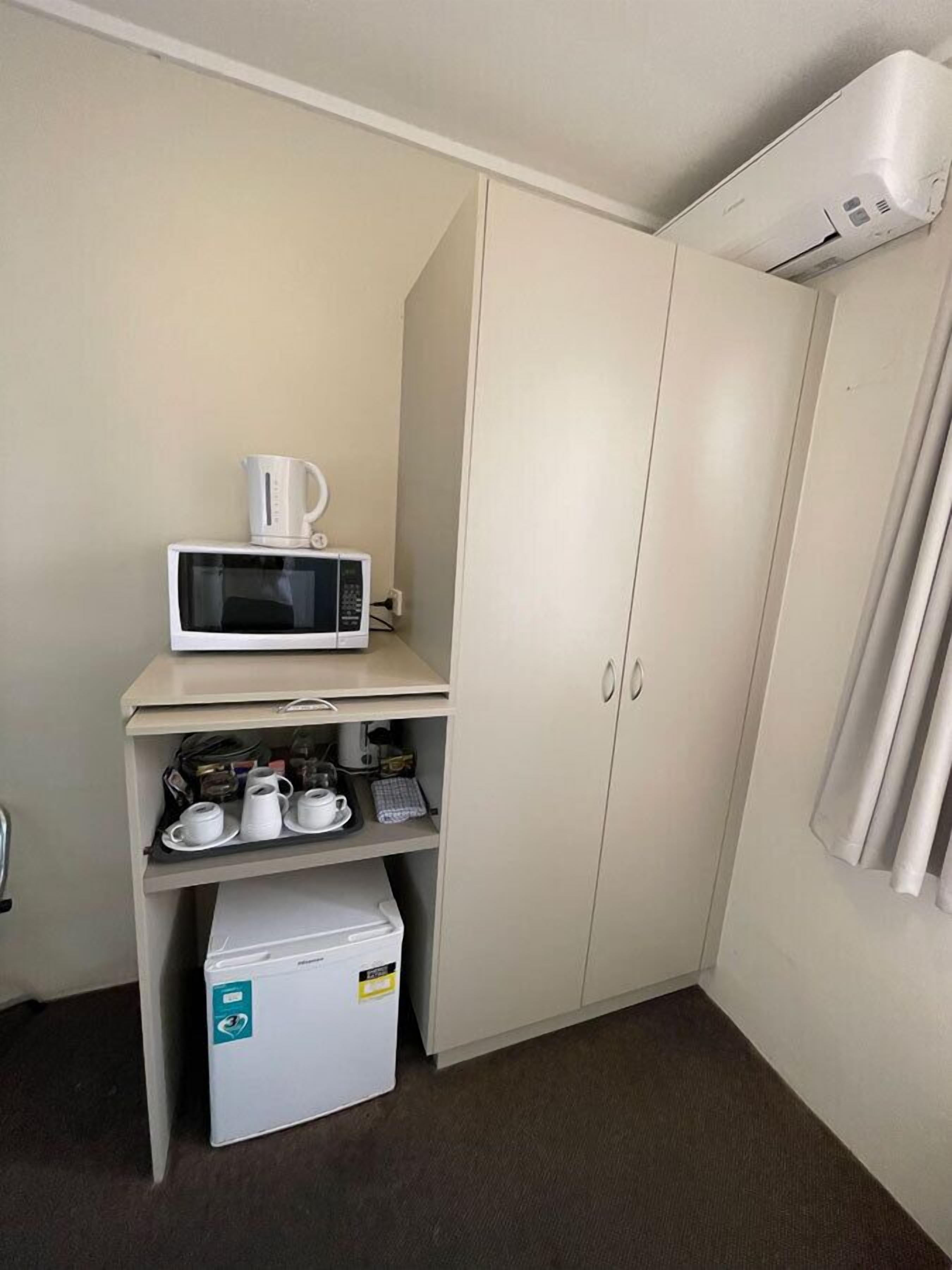 Eine Küchenzeile mit Mikrowelle, Kaffeemaschine und kleinem Kühlschrank.