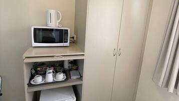 Eine Küchenzeile mit Mikrowelle, Kaffeemaschine und kleinem Kühlschrank.