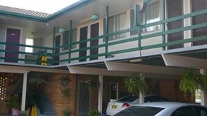 Un motel de dos pisos con estacionamiento techado y varias habitaciones.