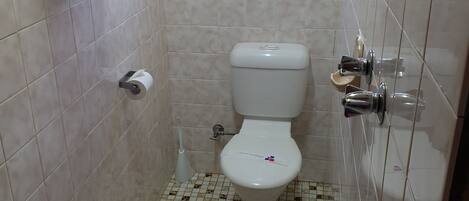 A small bathroom with a toilet, a hand dryer, and a window.