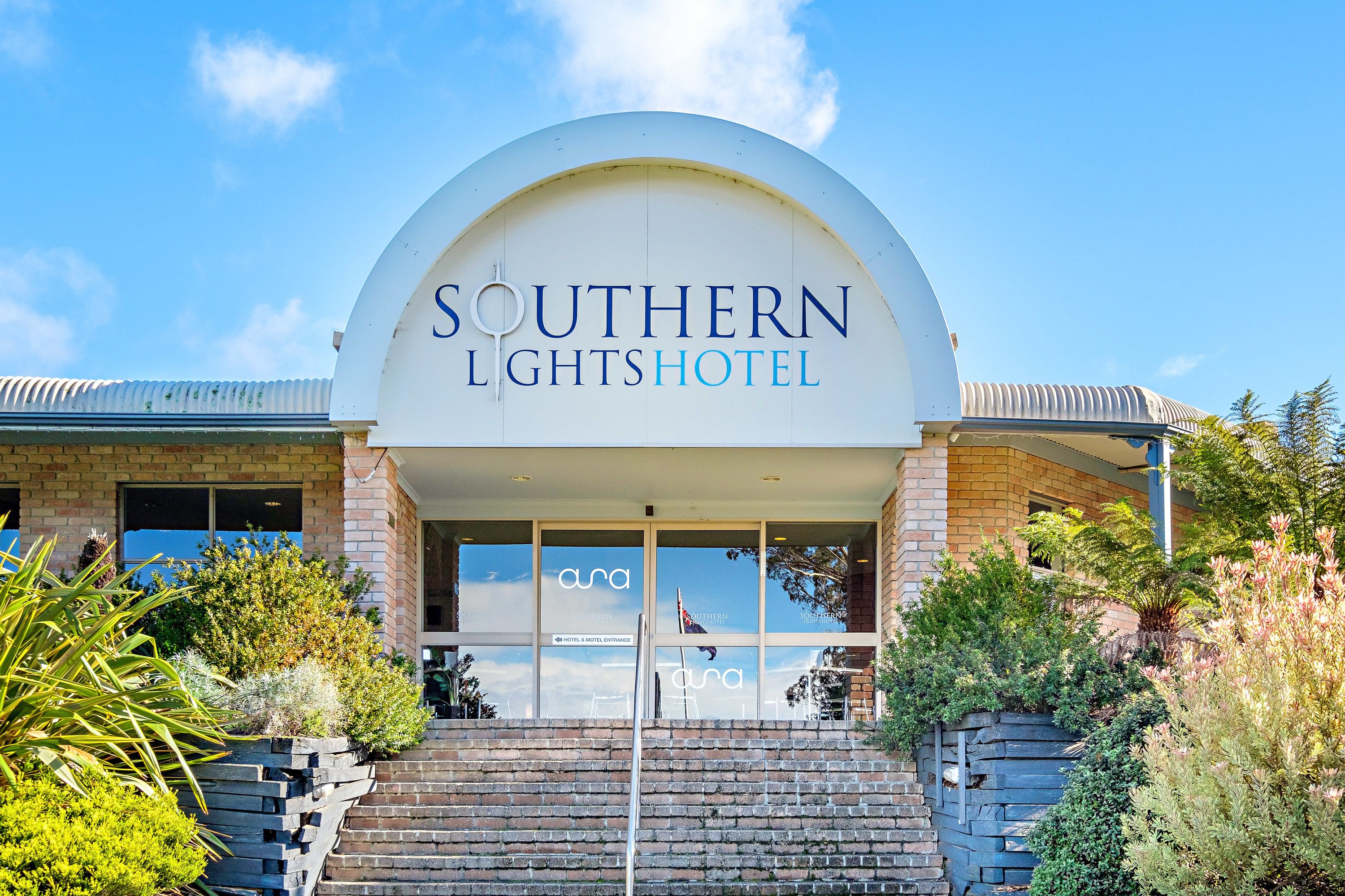 The Southern Lights Hotel entrance with a clear sky, brick facade, and steps leading up to the entrance.