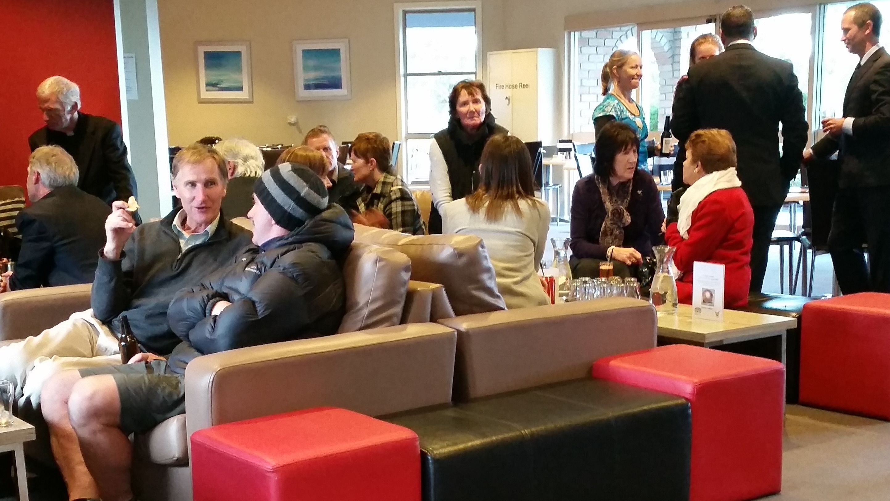A social gathering in a modern indoor space with seating arrangements and tables.