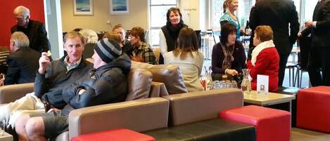 A social gathering in a modern indoor space with seating arrangements and tables.