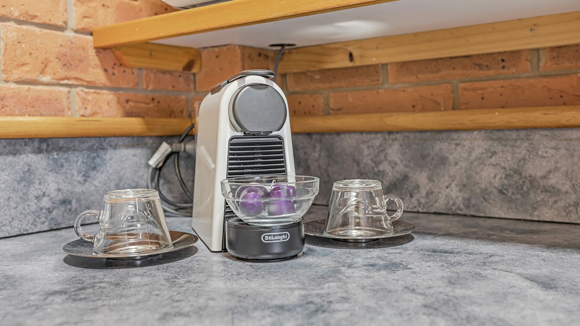 Een koffieapparaat met twee glazen bekers op een marmeren aanrecht.