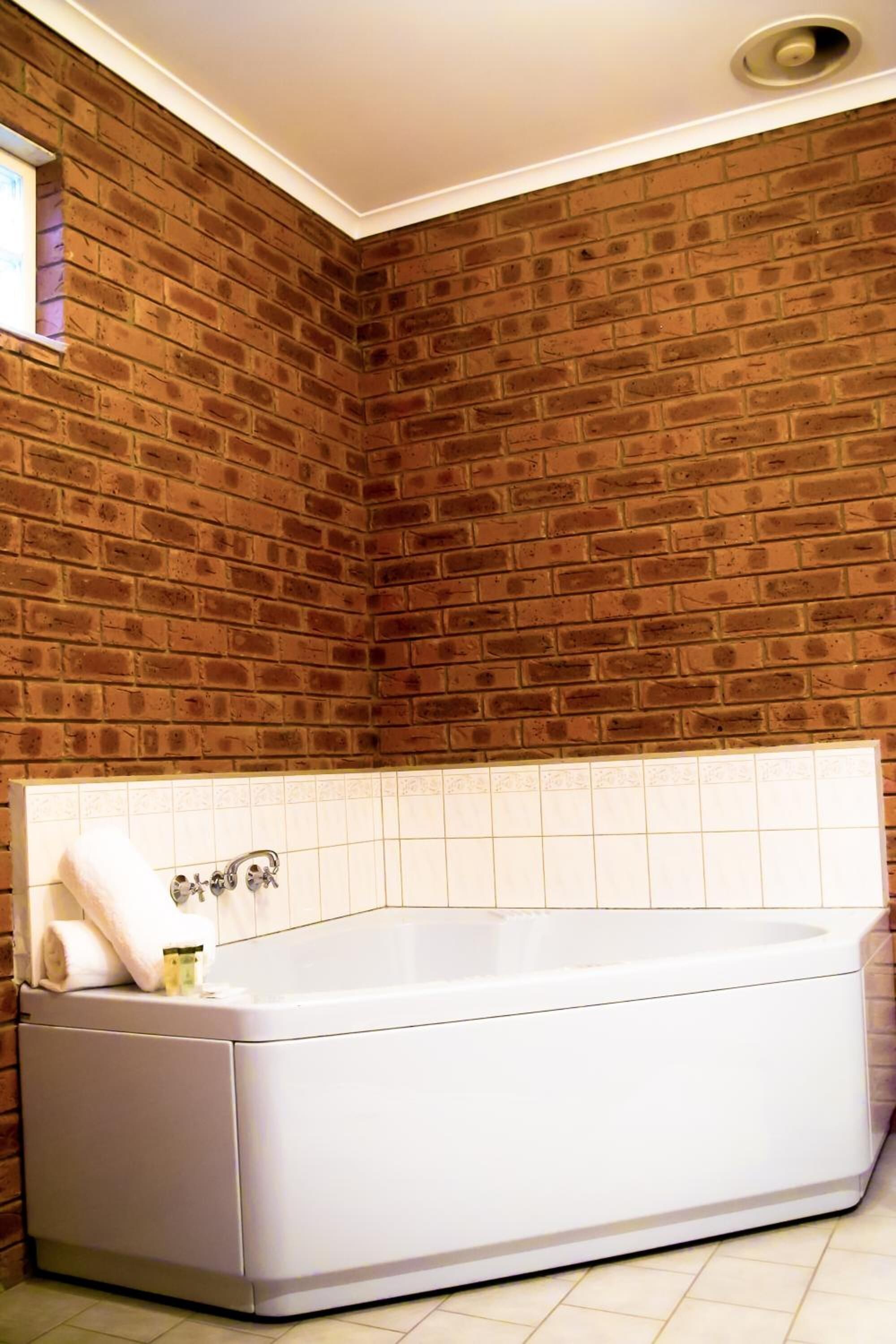 A bathroom with a white bathtub, a tiled wall, and a visible shower area.