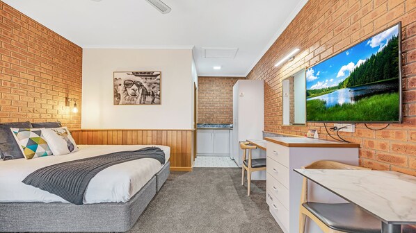 A compact room with a bed, a small kitchenette, and a TV mounted on the wall. - Golden River Motor Inn (Moama)