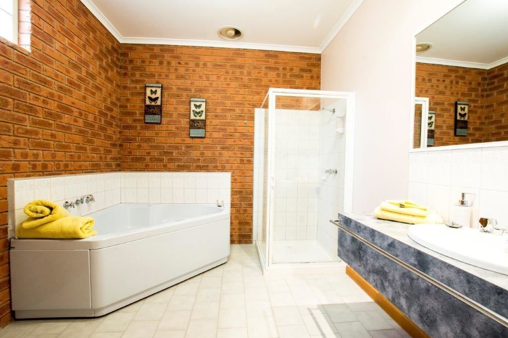 A bathroom with a white bathtub, a glass shower enclosure, and a marble vanity with a sink.