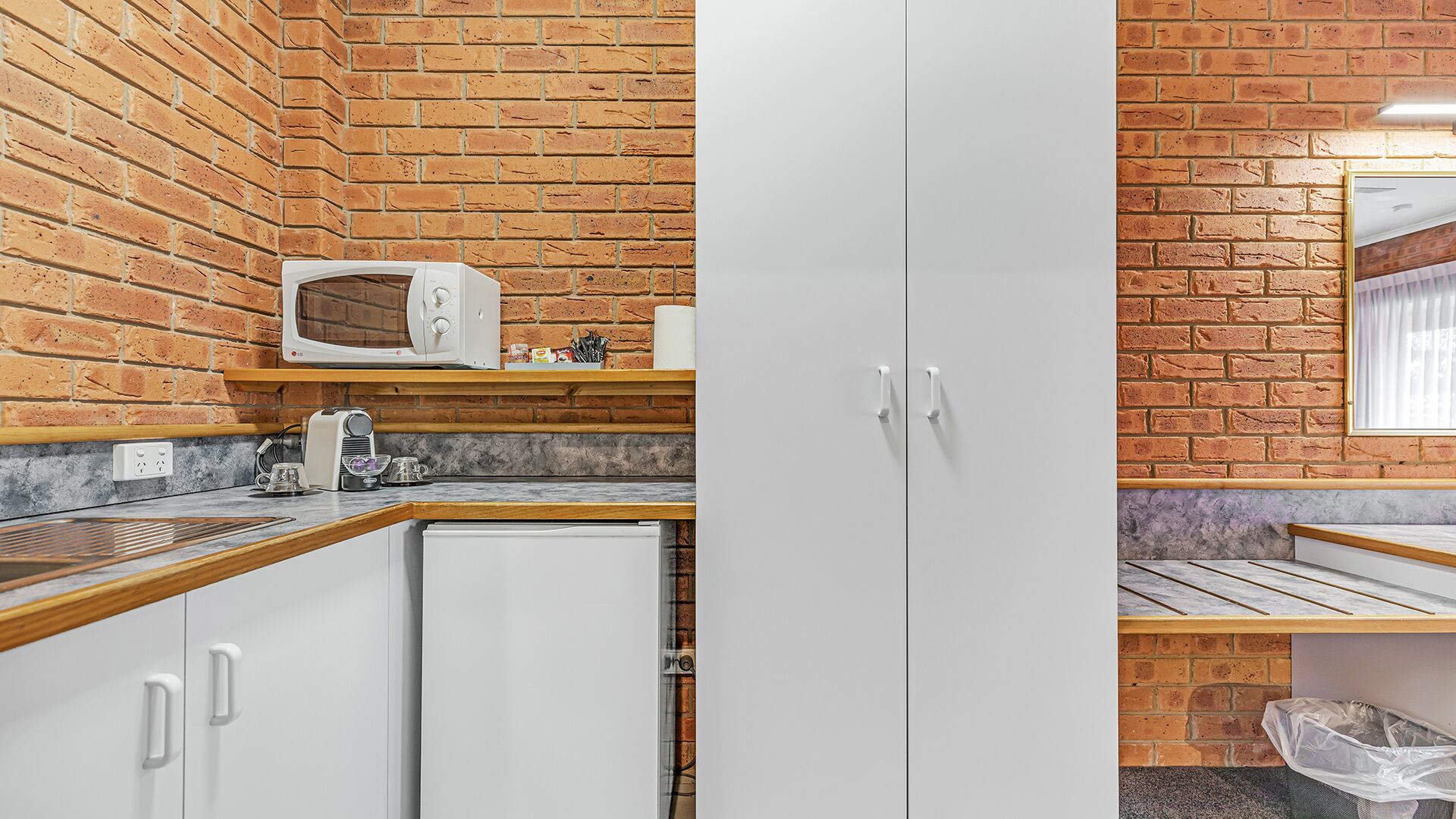 A compact kitchen with a microwave, a coffee maker, and a small refrigerator.