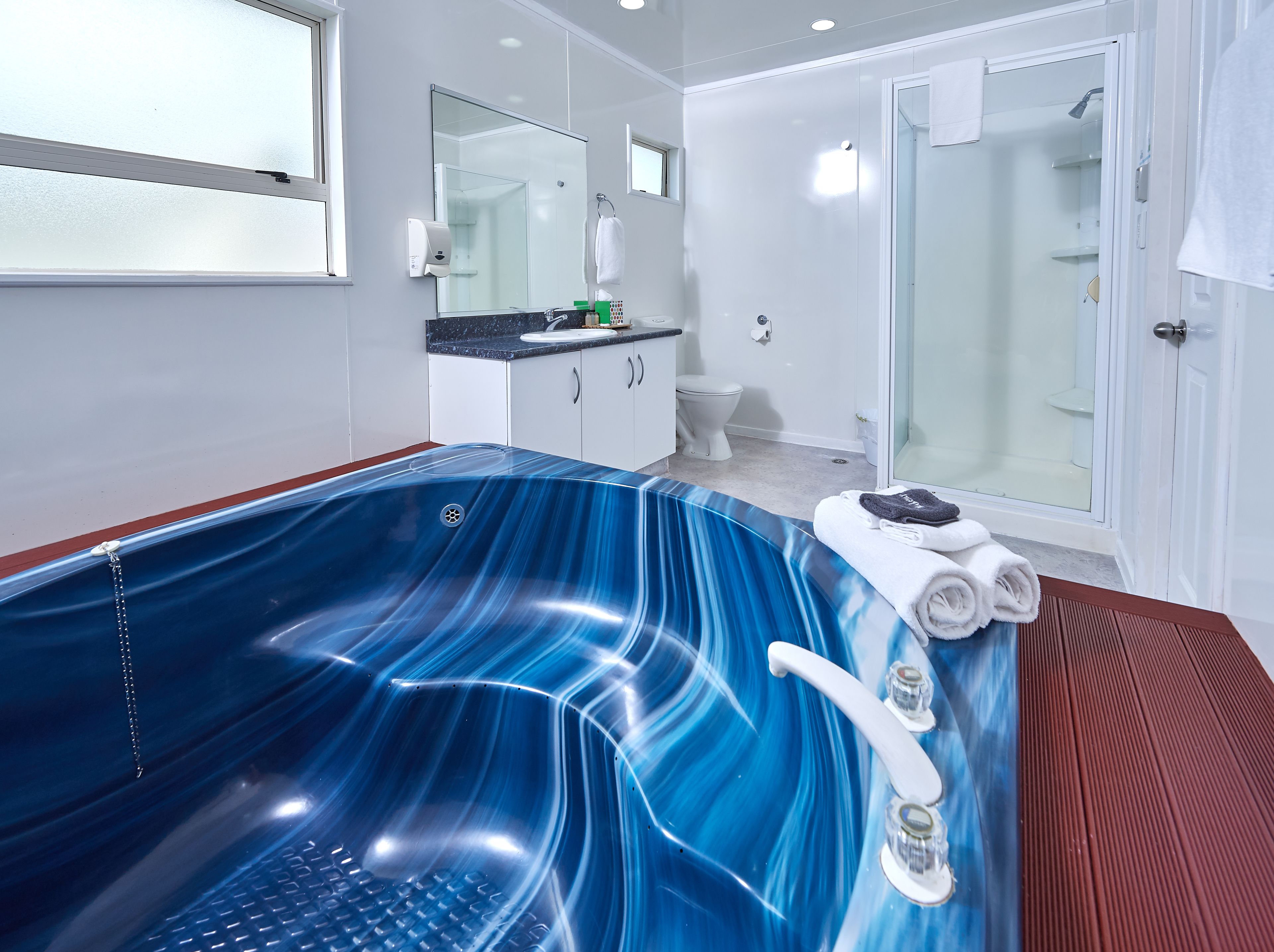 A modern bathroom with a large bathtub, a toilet, and a shower area.