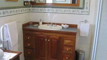 Ein Badezimmer mit einem Holztischchen, einem Waschbecken und einem Spiegel darüber.