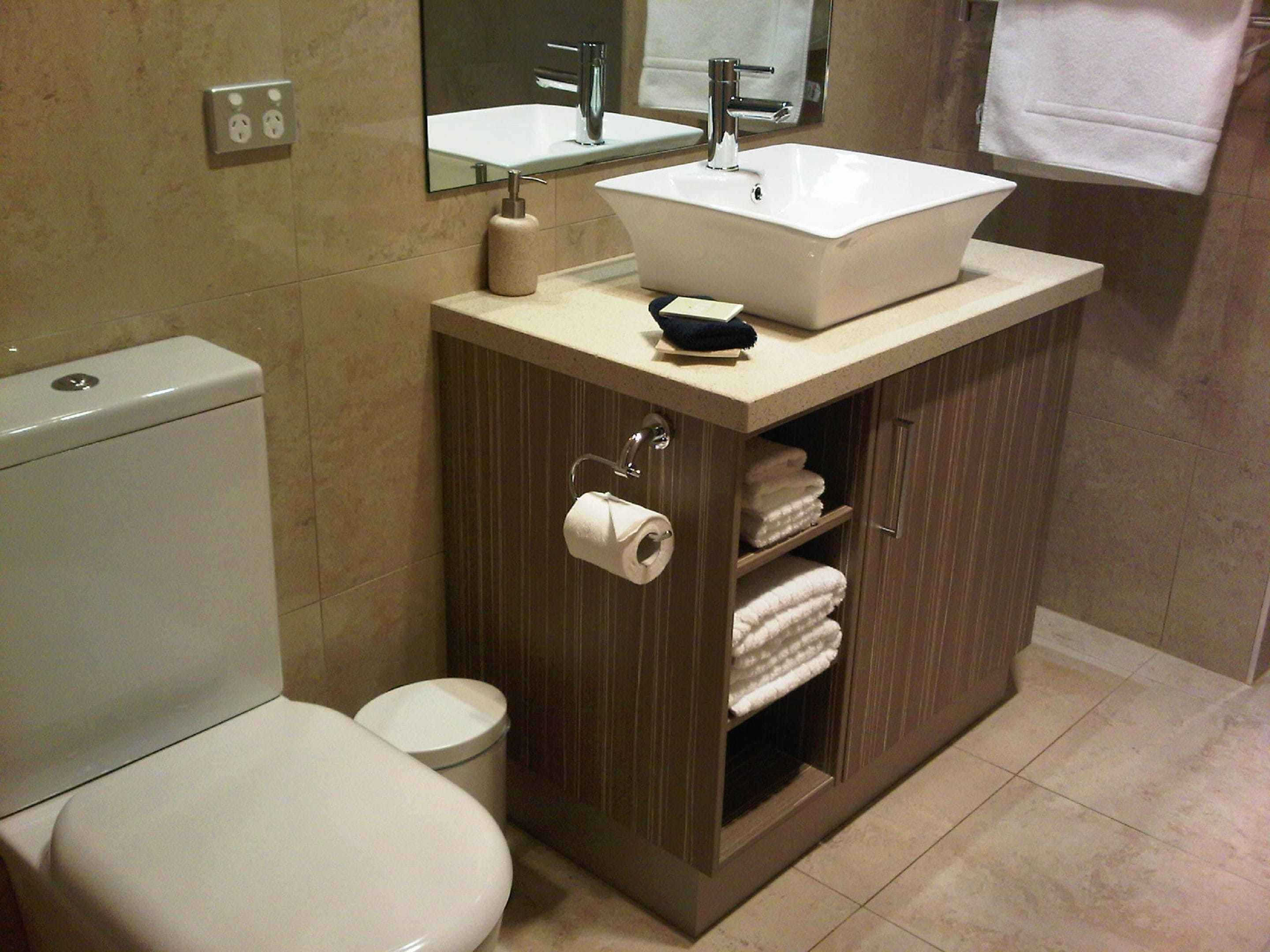 Un baño con inodoro, lavamanos y espejo.