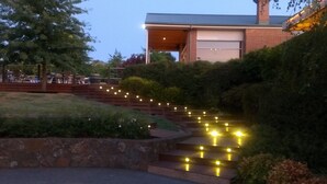A building with a garage door, surrounded by a landscaped area with steps and string lights.