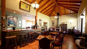 A spacious dining area with high ceilings and wooden beams, featuring a bar and multiple seating options.