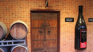 A cellar door reception with wooden barrels and a wine bottle.