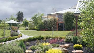 A landscaped garden with a gazebo, a modern building, and a pathway.