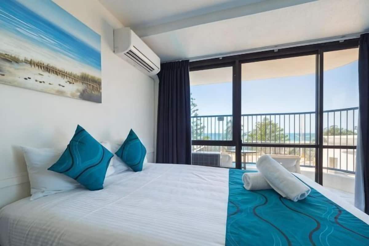 Una habitación de hotel con cama, un cuadro, un balcón con vistas y una ventana.
