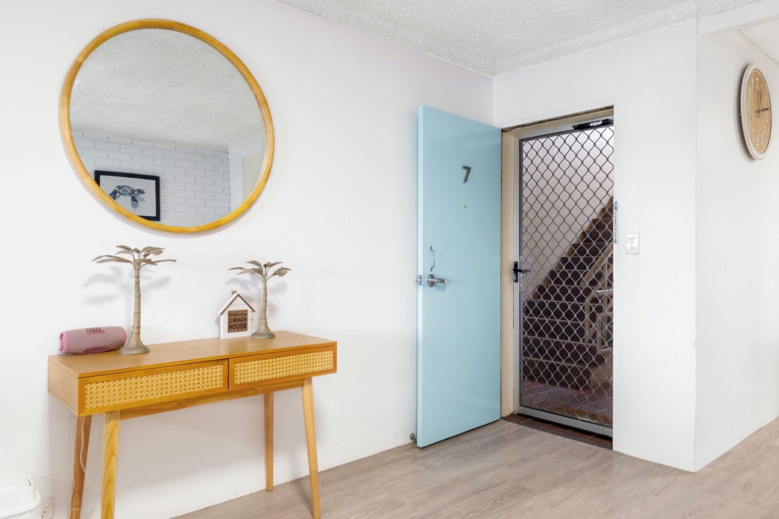 A room with a wooden console table, a blue door, and a large mirror.