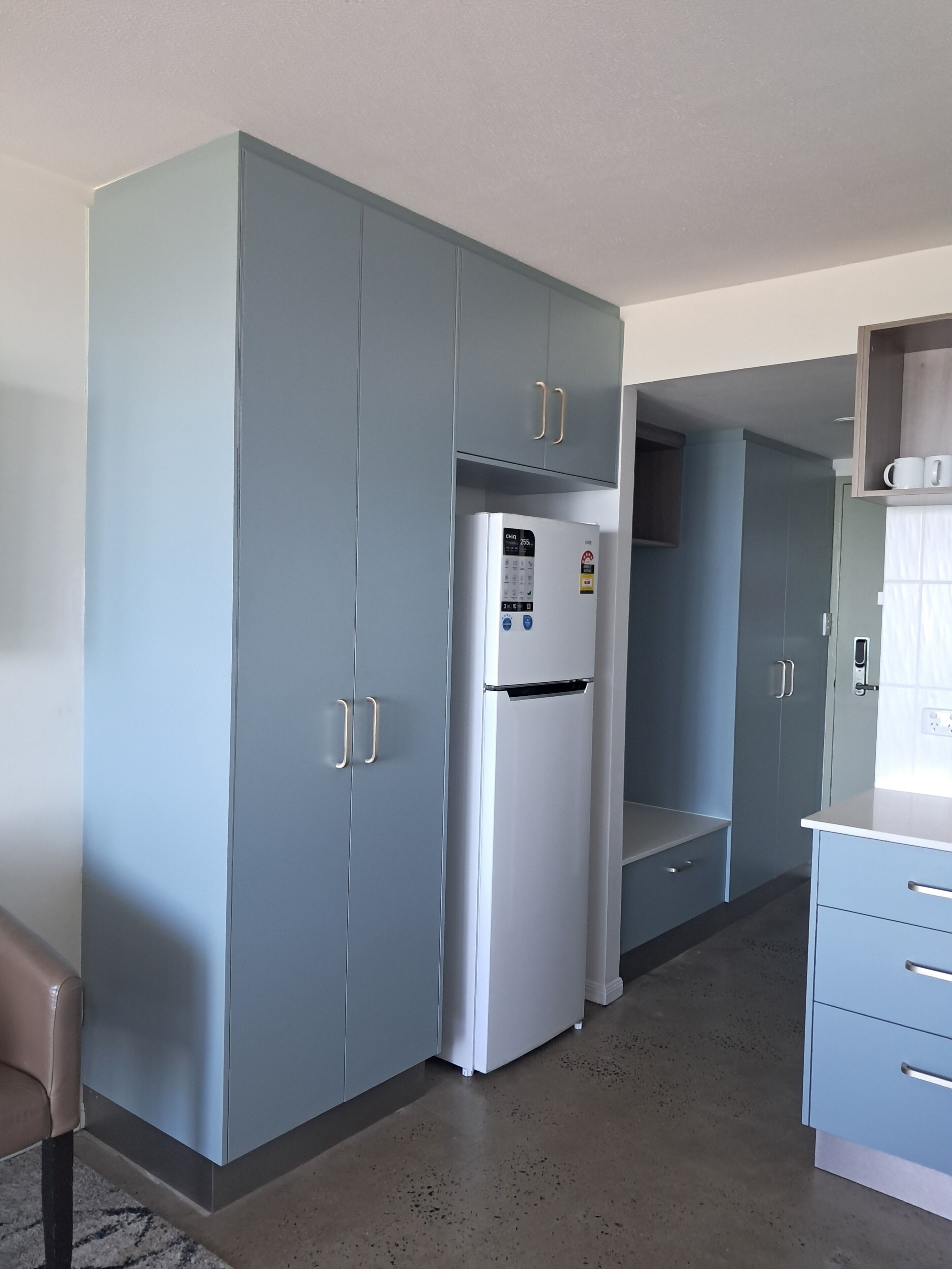 Eine moderne Küche mit grauen Schränken, einem Edelstahlkühlschrank und einer Arbeitsplatte.