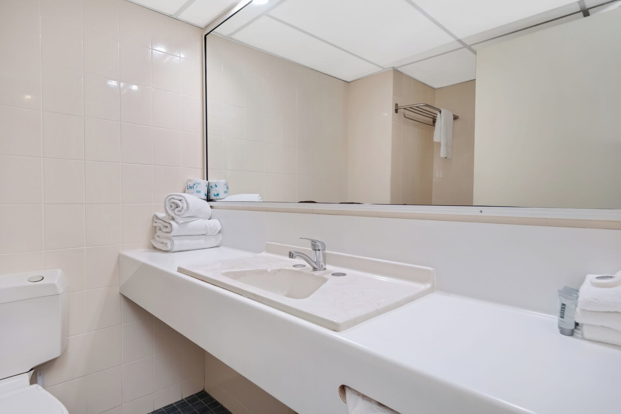 Un baño moderno con un lavabo blanco, un espejo y un perchero para toallas.